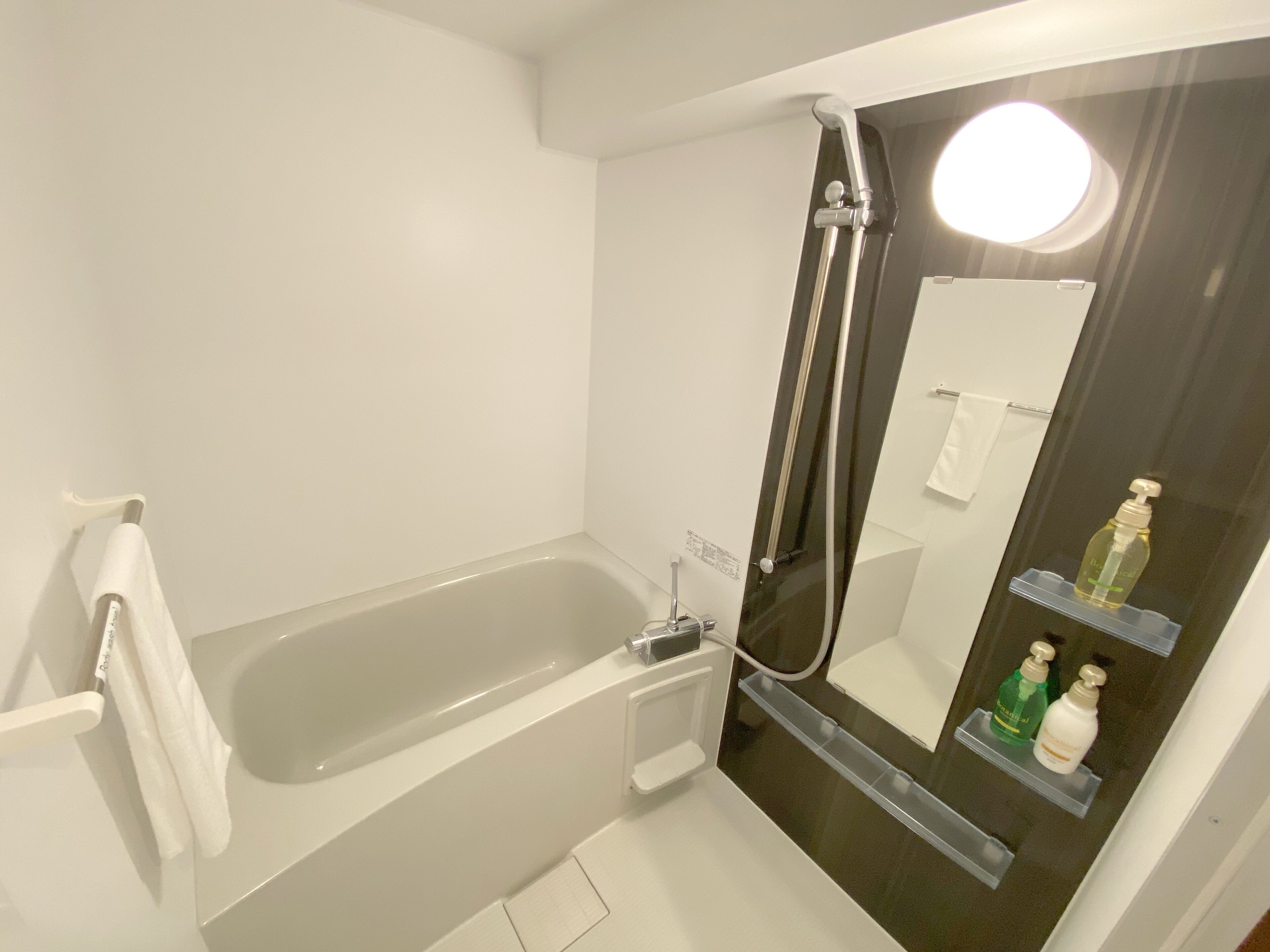 A modern bathroom with a bathtub, a glass-enclosed shower, and a mirror with a built-in light.