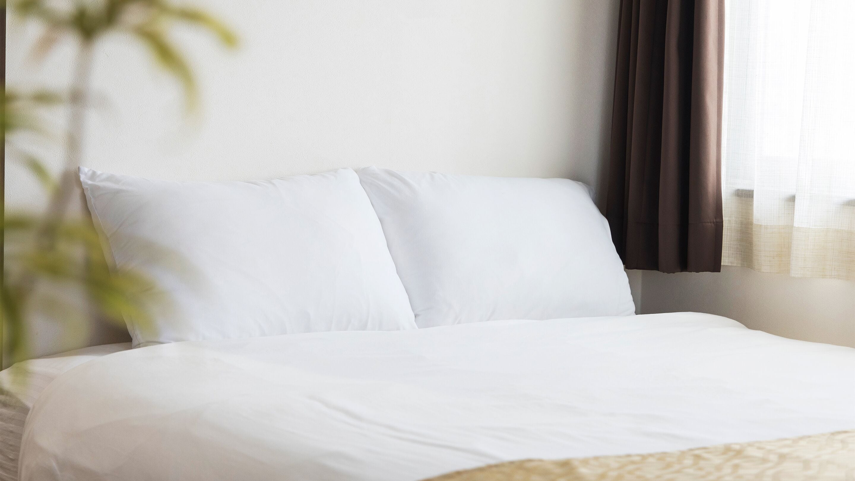 A neatly made bed with white linens in a hotel room.