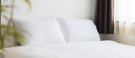 A neatly made bed with white linens in a hotel room.
