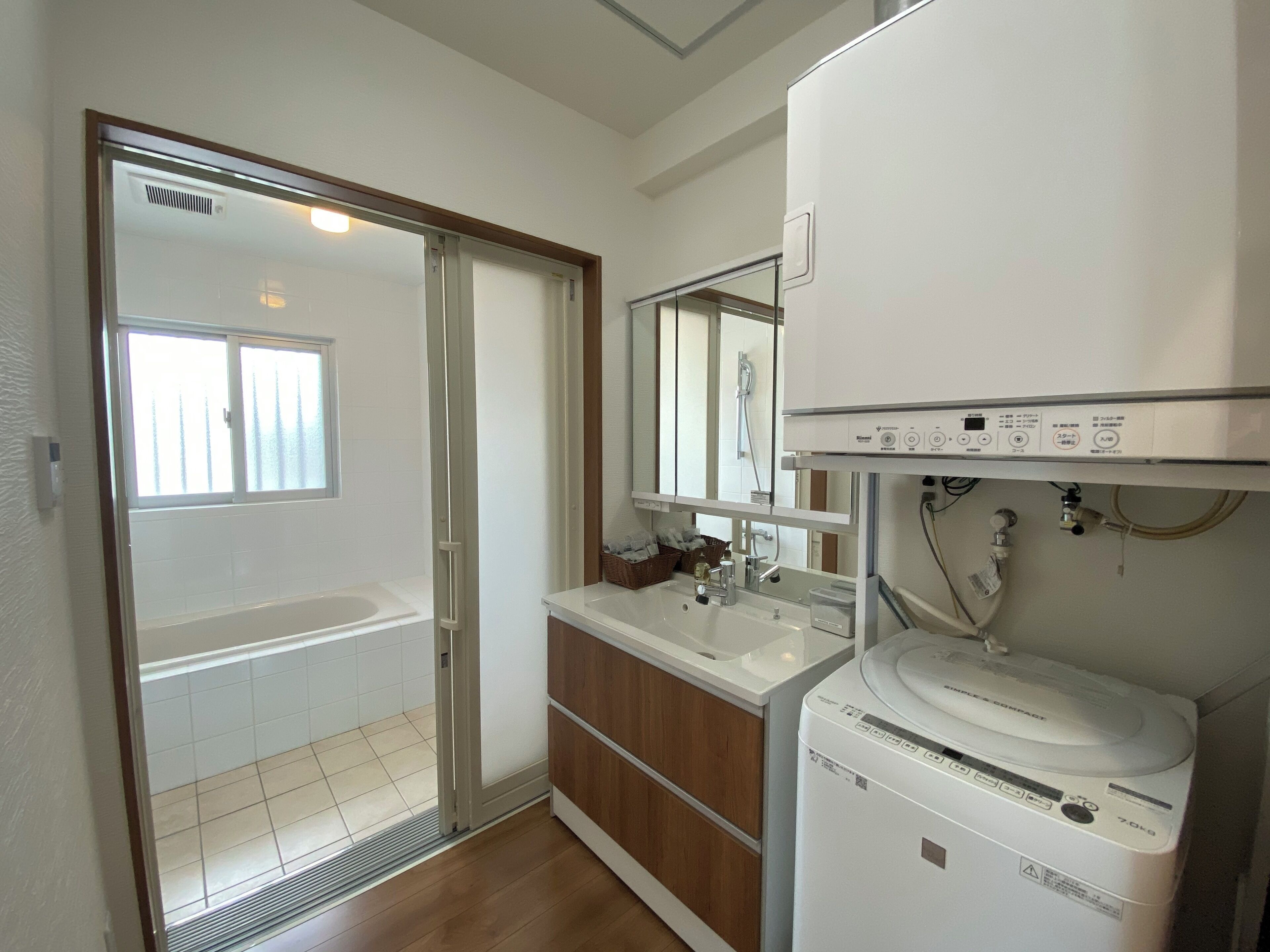 A bathroom with a shower, a sink, and a washing machine.
