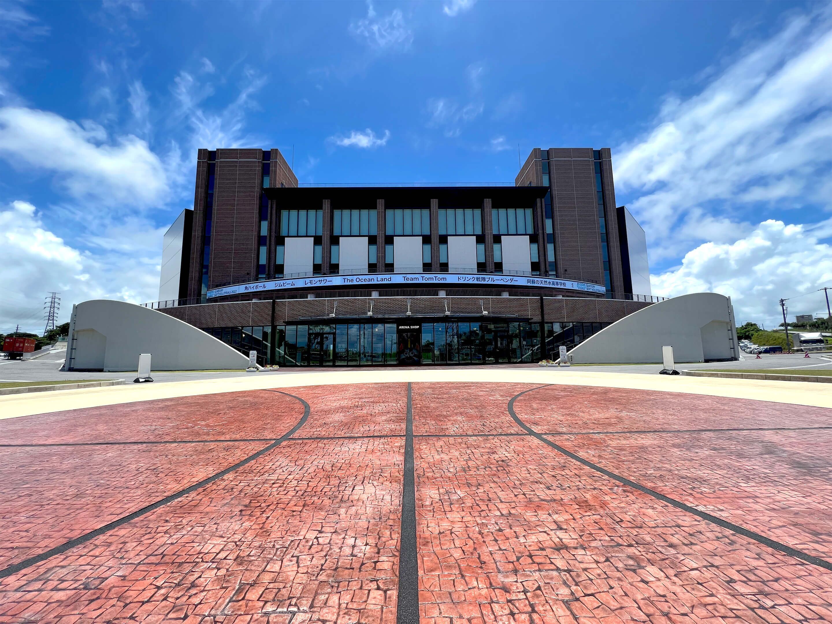 A modern building with a curved entrance and a brick pathway leading to it.