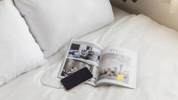 A magazine open on a bed with a smartphone charging, featuring a modern living room interior.