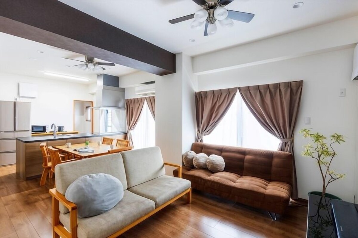 Una sala moderna con un sofá, una mesa de comedor y una cocina al fondo.
