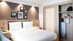 A hotel room with a large bed, bedside tables, a wardrobe, and framed pictures on the wall. - Hampton by Hilton Berlin City East Side Gallery (Berlin)