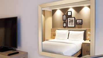 Una habitación de hotel con una cama, un televisor y un espejo que refleja la habitación.