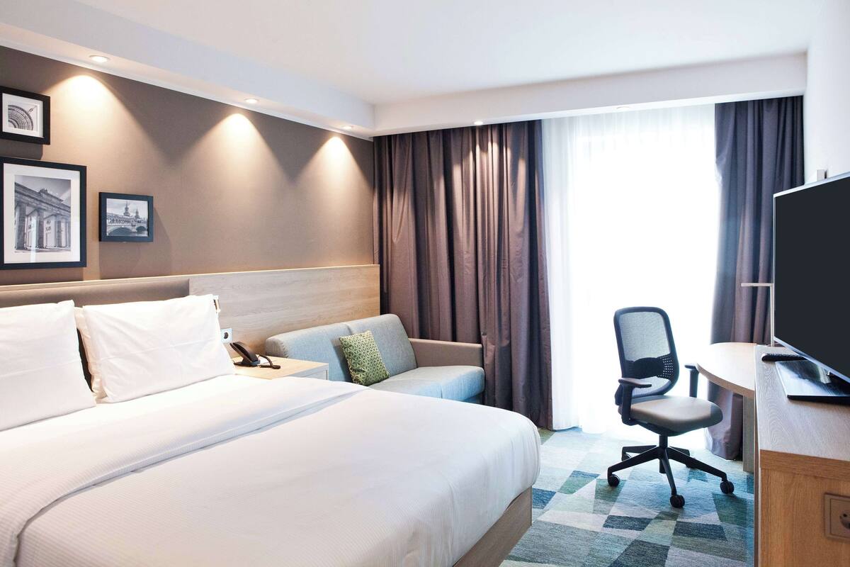 Una habitación de hotel con una cama grande, un escritorio, una silla y un televisor.