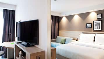 Una habitación de hotel con cama, televisor, escritorio con silla y una mesita.