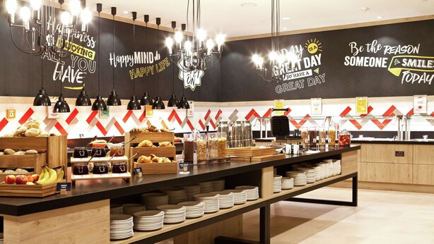 Zona de bufé con diversas opciones de comida y una pared decorativa con mensajes inspiradores.