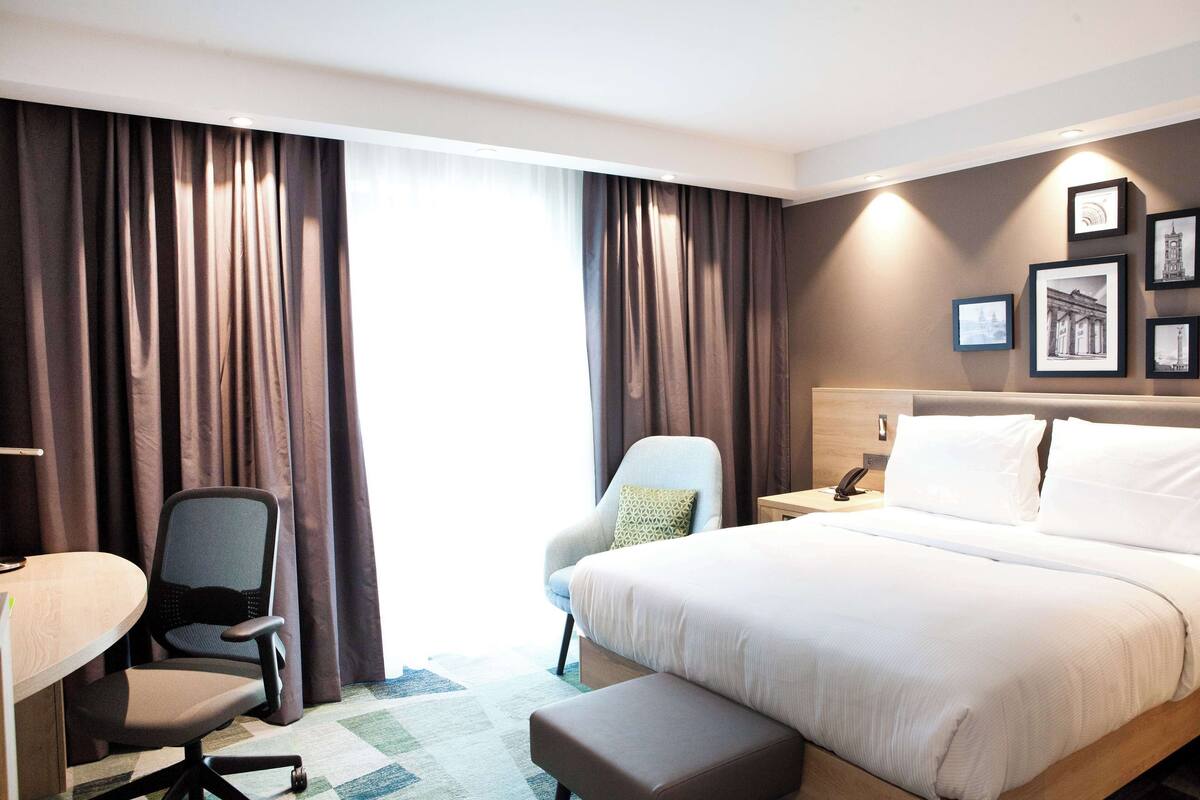 Habitación de hotel con una cama grande, dos sillas, un escritorio y una mesita de noche.