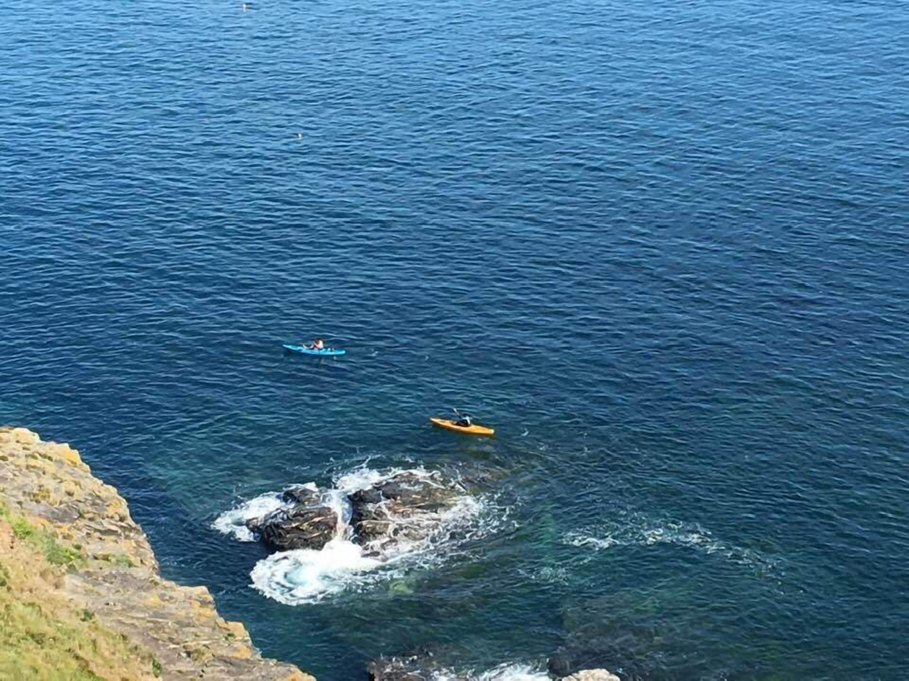 Un paysage côtier avec des kayaks sur l’eau.