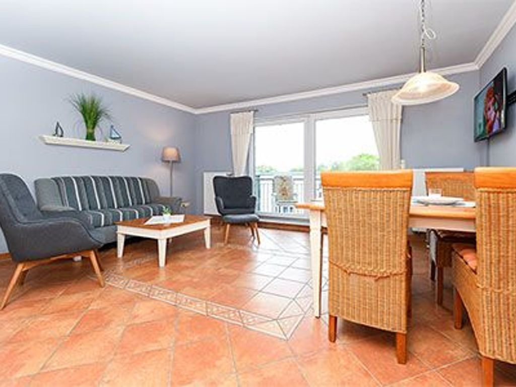 A living room with a sofa, chairs, a coffee table, and a dining area with a table and chairs.