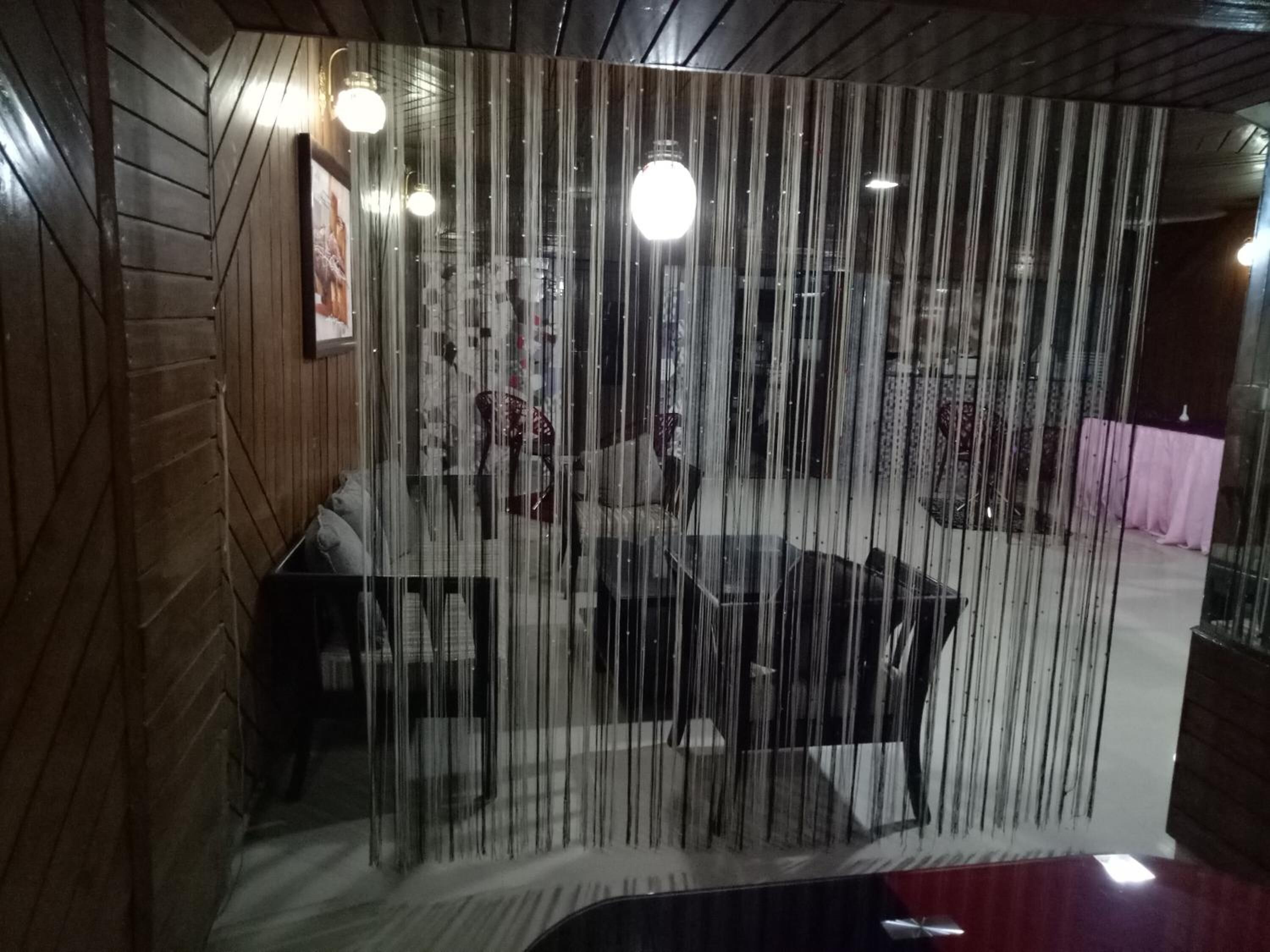 Een kamer met een houten wand, een glazen scheiding en een tafel met stoelen.