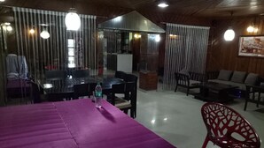 A dining area with a purple tablecloth, a water bottle, and a red chair. - Hotel Kameng (Papumpare)