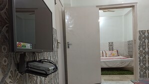A room with a bed, a small table, and a door leading to another room. - Hotel Kameng (Papumpare)