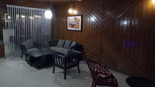 A room with a wooden herringbone wall, a sofa, a dining table, and chairs. - Hotel Kameng (Papumpare)