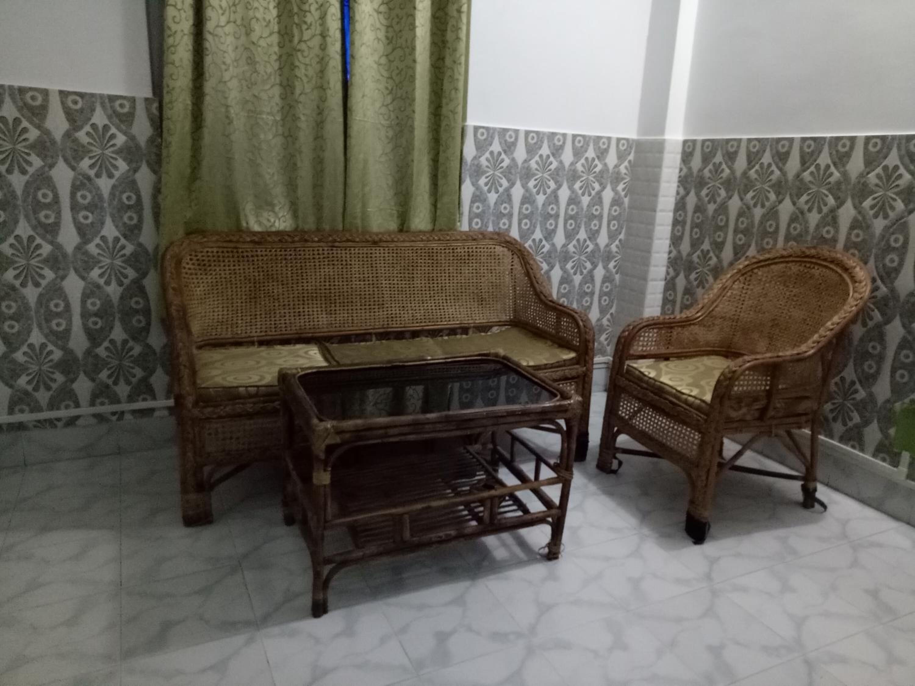 Une pièce avec un mur orné de motifs, un canapé, un fauteuil et une petite table.