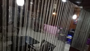 A room with a glass partition, a table, chairs, and a pink sofa. - Hotel Kameng (Papumpare)