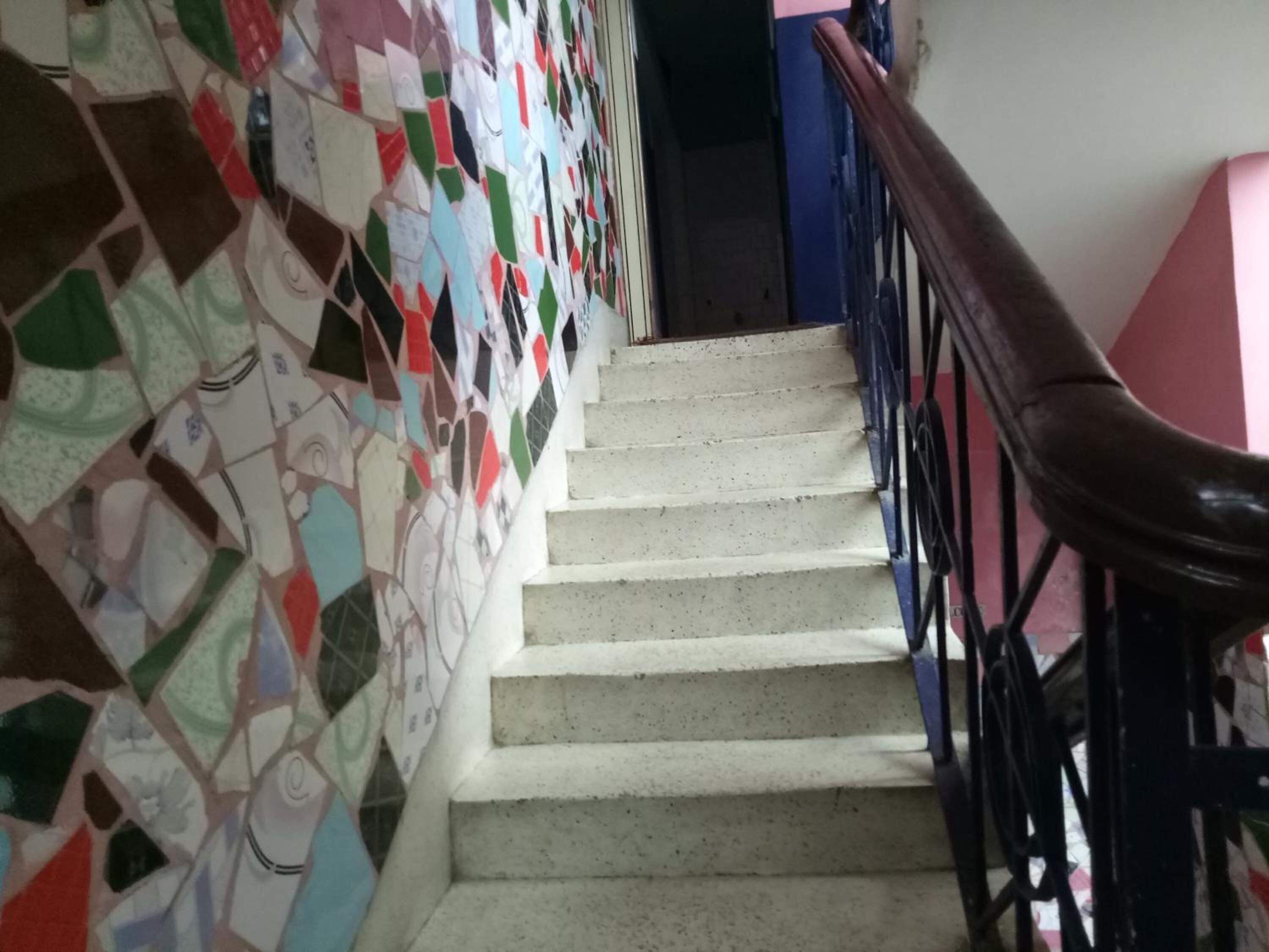 Una scala con ringhiera e parete decorata con piastrelle colorate.