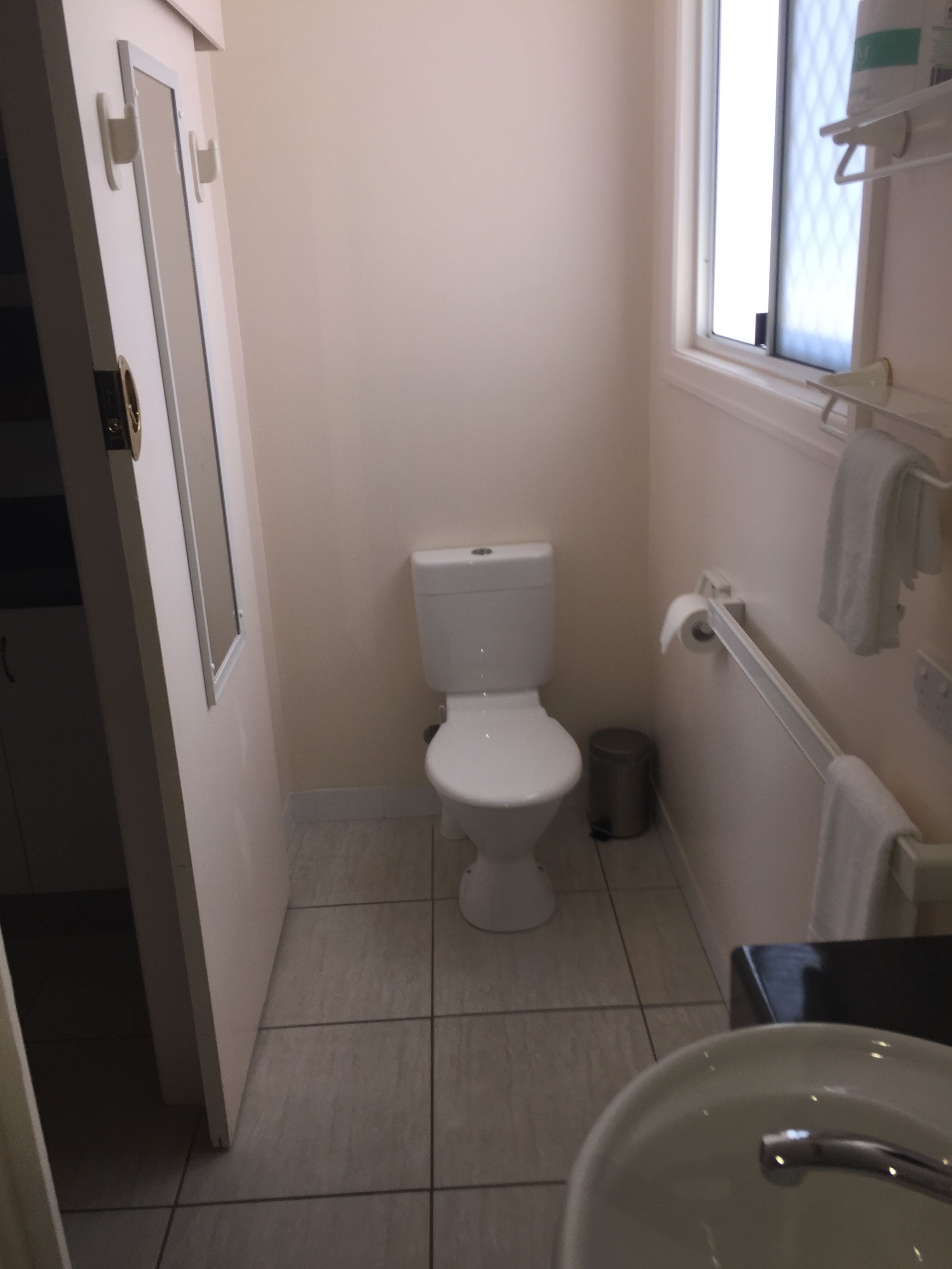 A small, clean bathroom with a toilet, a sink, and a window.