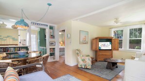 A cozy living room with a dining area, a bookshelf, and a wooden cabinet.