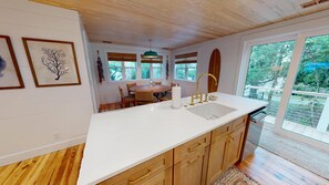 A kitchen with a large island, wooden cabinets, a white countertop, and a view of the outdoors.