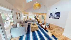 A spacious living room with a large sectional sofa, a coffee table, and a blue striped rug.