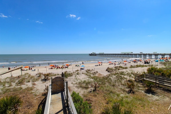 A beach with a wooden boardwalk leading to a pier.