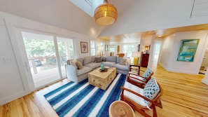 A spacious living area with a large sofa, a wooden coffee table, and a blue striped rug.