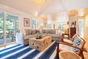 A spacious living room with a large sectional sofa, a wooden coffee table, and a striped area rug.