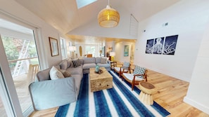 A spacious living room with a large sectional sofa, a coffee table, and a blue striped rug.