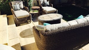 A wicker outdoor seating area with a pool, including two chairs and a sofa.