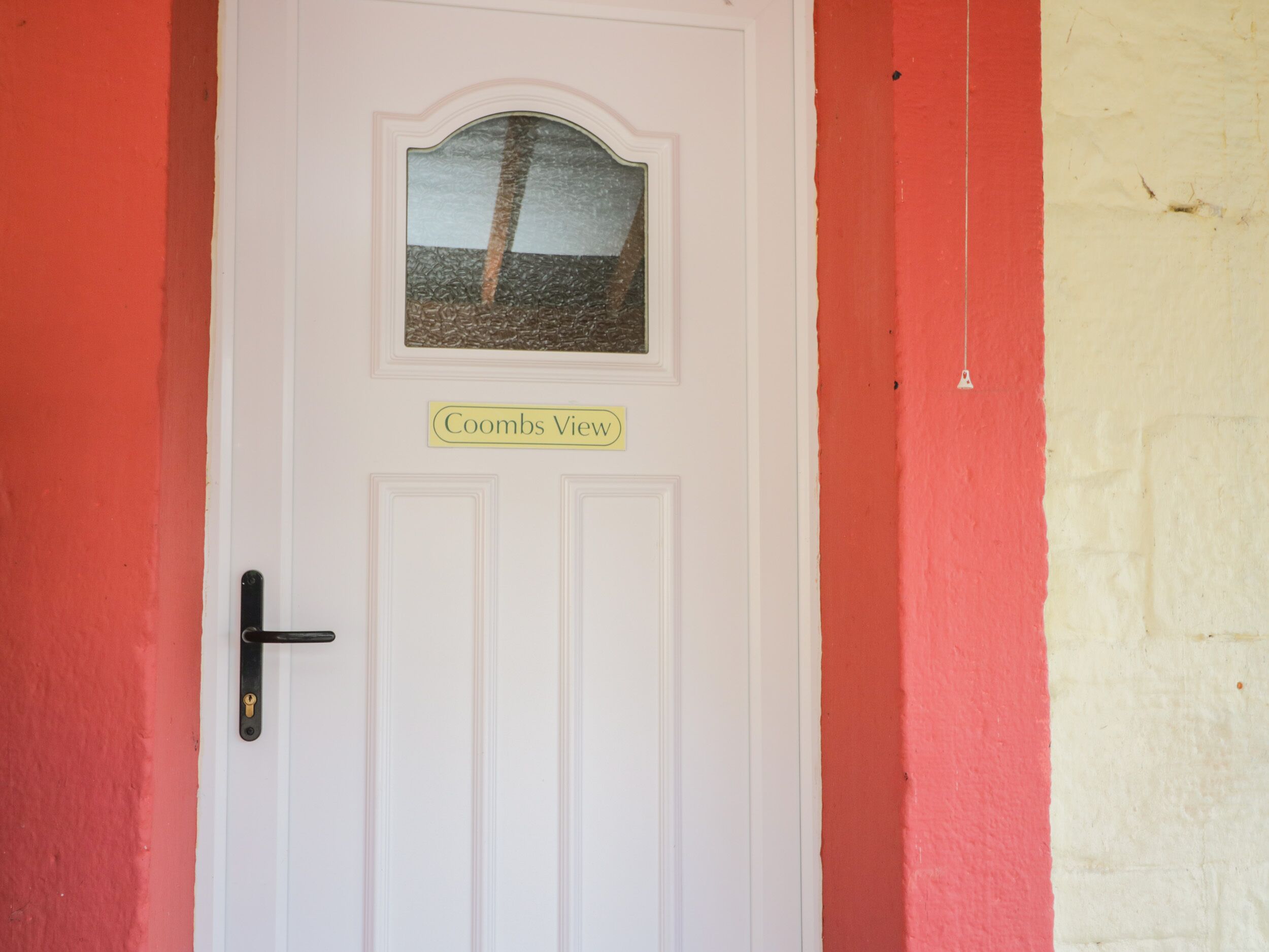A white door with a small picture of a landscape and the text 'Coombs View' above it.