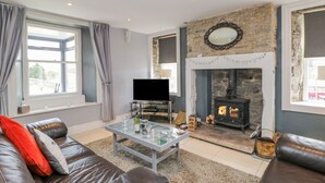 A living room with a stone fireplace, leather sofa, and a television. - 1 Braeside (Bishop Auckland)