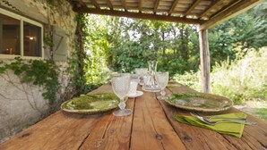 A wooden table set outdoors with plates, glasses, and cutlery. - La Cannara (Marta)