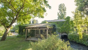 A rustic wooden structure with a tiled roof, a stone bridge, and a river. - La Cannara (Marta)
