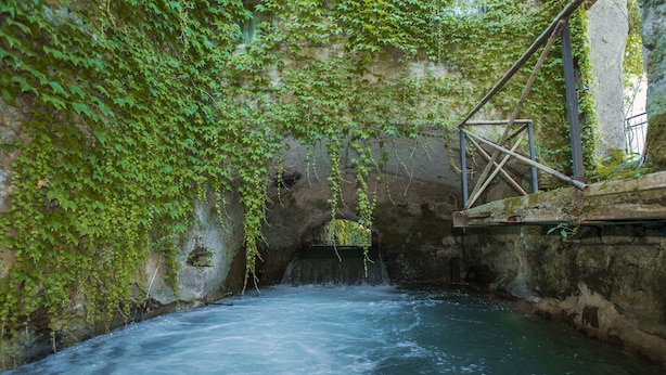 A river flowing through a stone structure with a metal staircase on the right. - La Cannara (Marta)