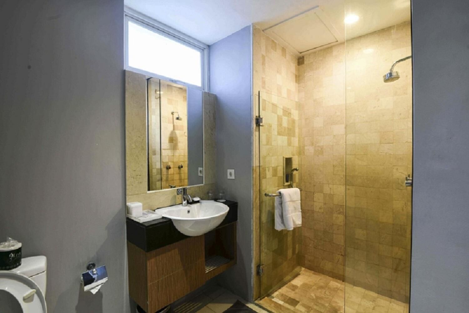 A modern bathroom with a large mirror, two sinks, a shower, and a toilet.