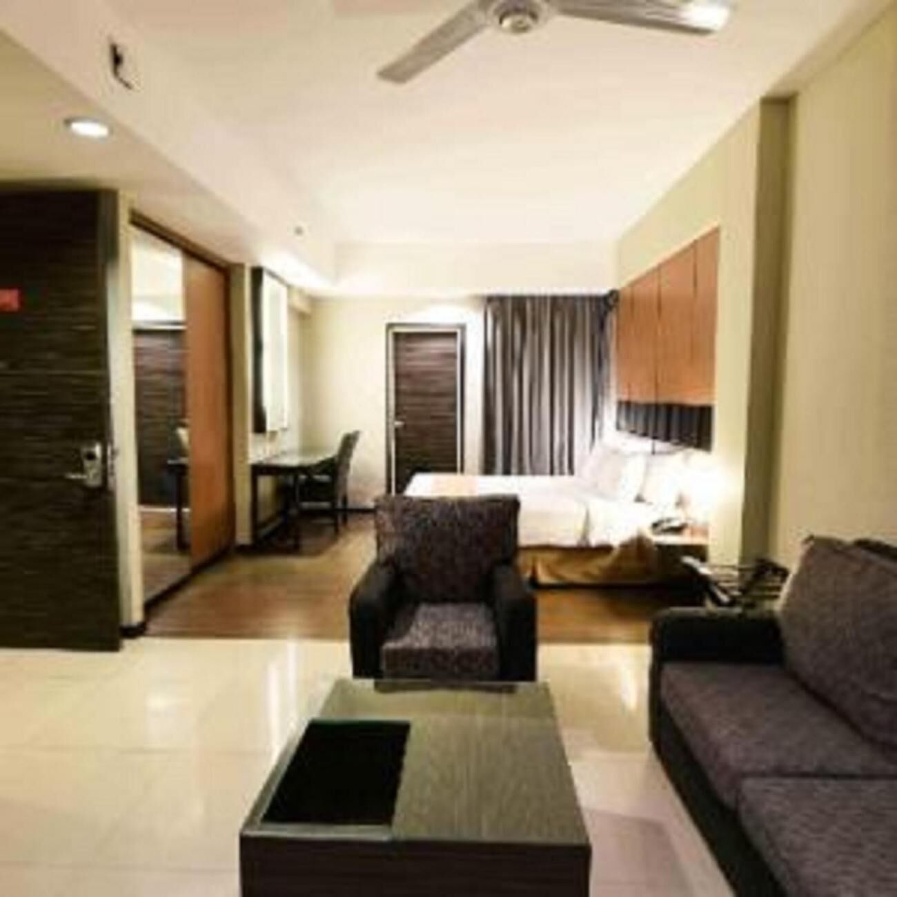 A hotel room with a bed, a sofa, a coffee table, a desk, and a chair.