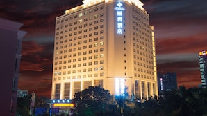 A high-rise hotel with multiple floors, illuminated windows, and a prominent sign on the side. - Rivan Hotel Longgang Shenzhen (Shenzhen)
