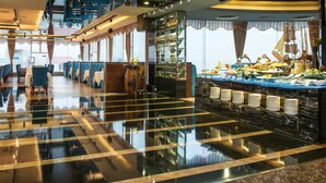 A hotel lobby with a polished black and gold floor, a buffet area with various food items, and a view of the city through large windows. - Rivan Hotel Longgang Shenzhen (Shenzhen)
