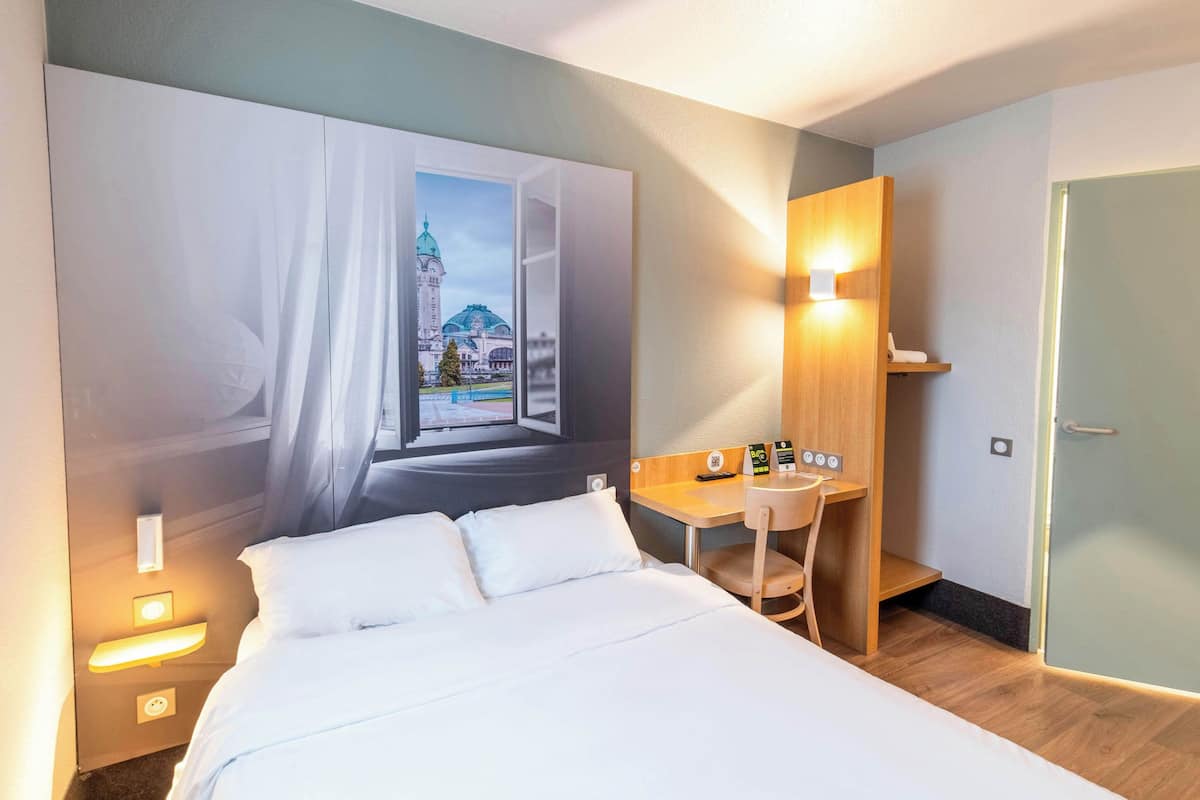Une chambre d’hôtel avec un grand lit, un bureau et un téléviseur fixé au mur.