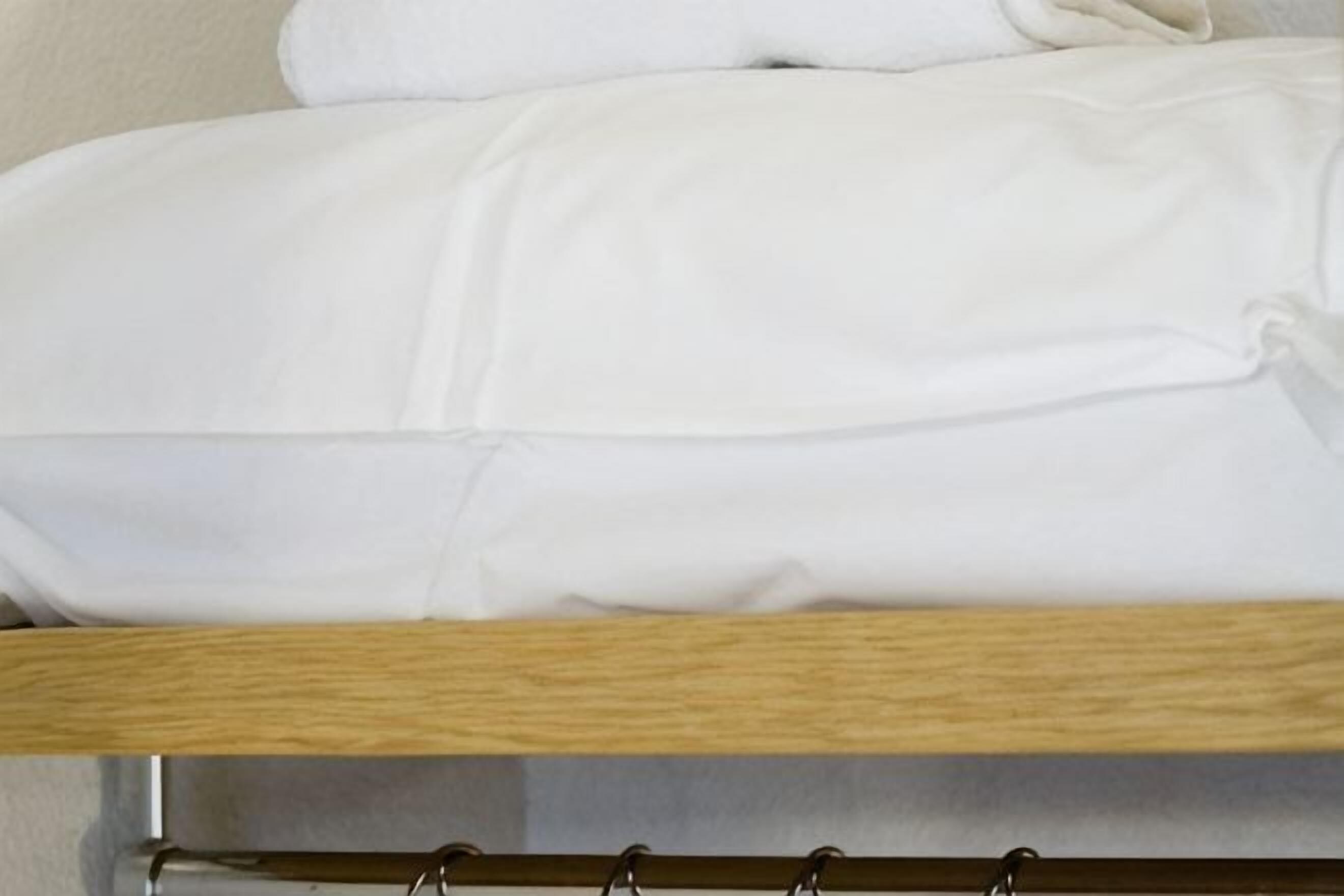 A bed with white bedding and a wooden headboard.