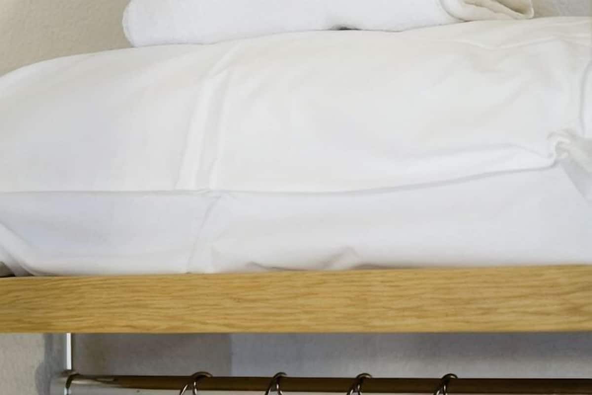 Un lit avec une literie blanche et une tête de lit en bois.