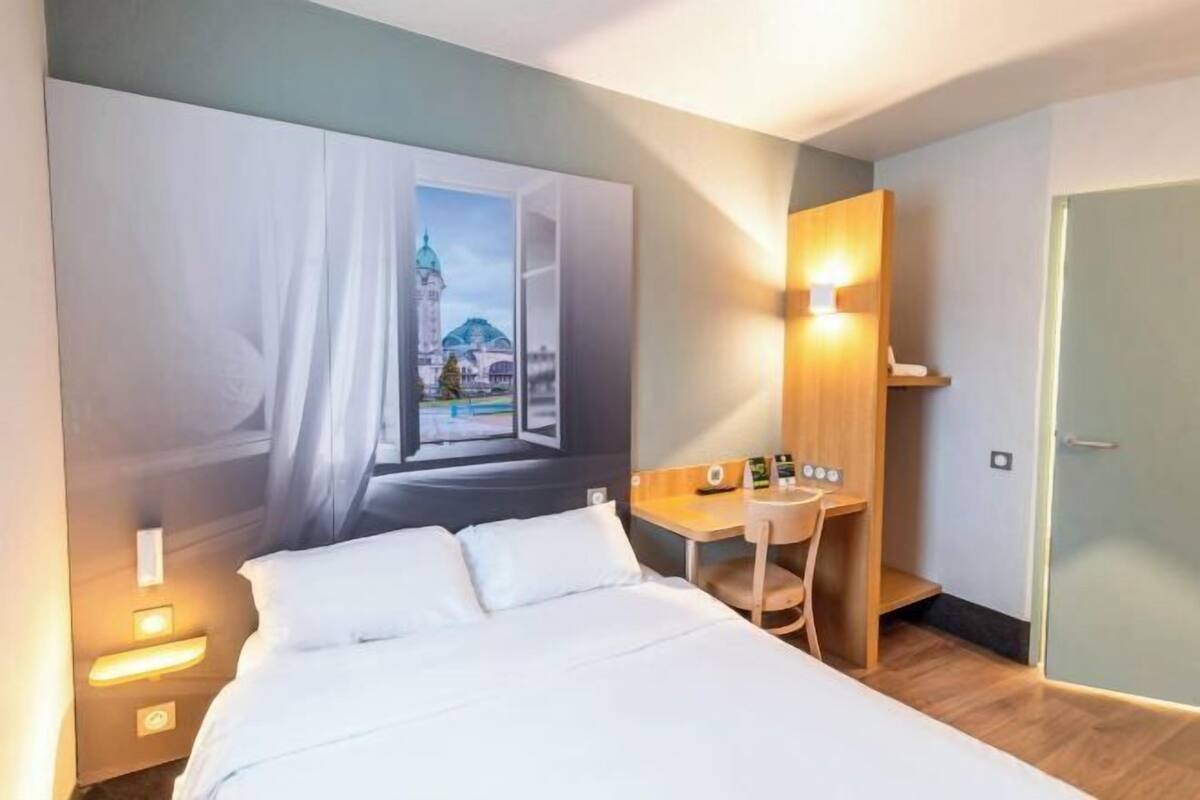 Une chambre d’hôtel équipée d’un lit, d’un bureau et d’un téléviseur fixé au mur.
