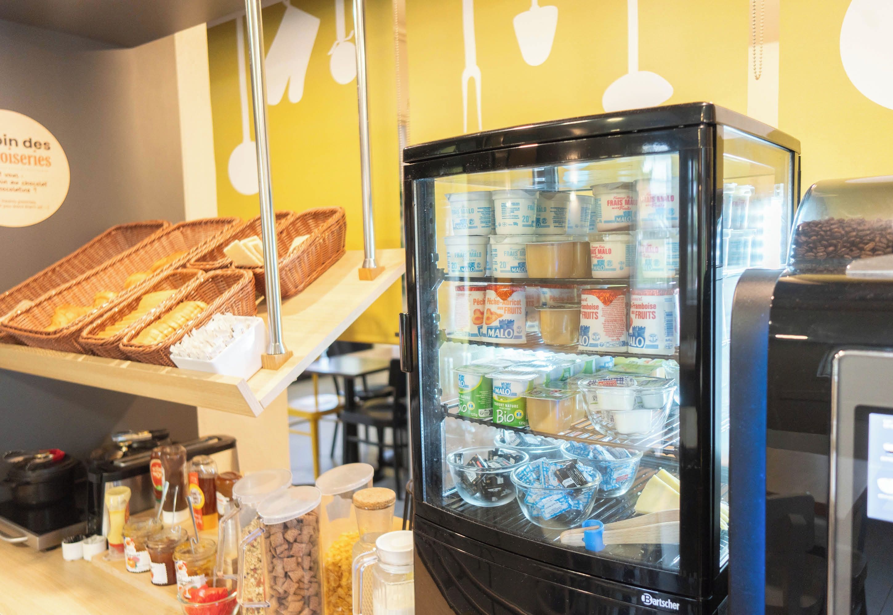 Un refrigerador exhibe diferentes productos alimenticios y un mostrador con cestas y aderezos.