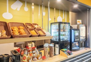 A breakfast buffet with baskets of pastries, a coffee machine, and various condiments. - B&B Hotel Limoges 1 (Limoges)