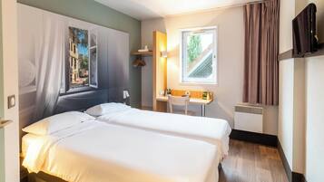 Hotelkamer met twee bedden, een bureau, een stoel, een televisie en een raam met gordijnen.