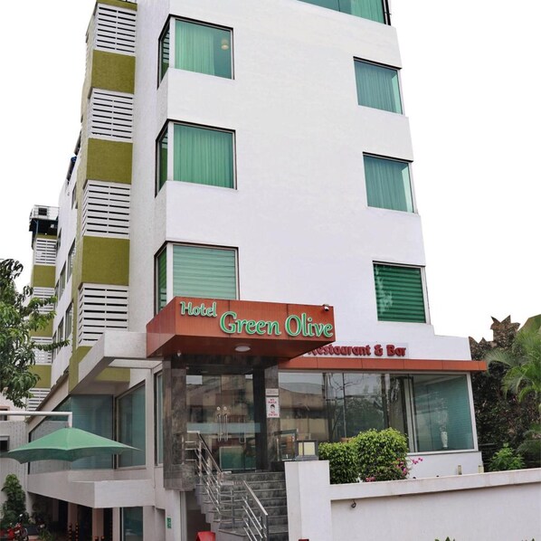 A multi-story hotel with a green and white facade, a visible restaurant and bar, and a staircase leading to the entrance. - Hotel Green Olive (AURANGABAD)