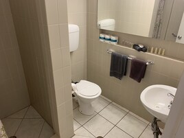 Un baño con inodoro, lavabo y repisas con artículos de tocador.
