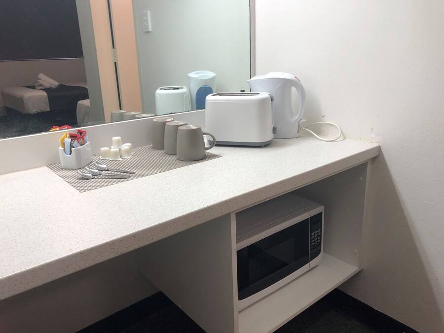 Un baño de hotel con encimera, microondas, hervidor y espejo.